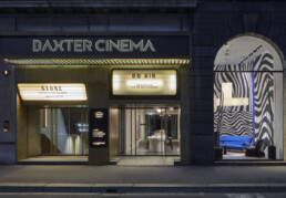 The Baxter flagship - called Baxter Cinema - occupies an old theatre in downtown Milan. Here it is shown in the evening, with the glow of signs labeled 