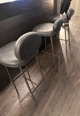 Three padded black bar stools with slightly different shaped and sized back rests - part of the Living Divani Pebble collection.
