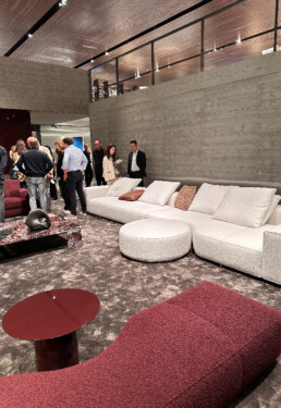 A living room setting at the Minotti Pavilion located at the Rho Fieramilano fairgrounds featuring two sofas, one in white and one in rhubarb.