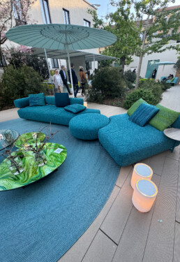 A large uniquely shaped outdoor seating system splays in the middle of a lush garden centre of the Paola Lenti flagship in Milan.