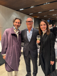 Three people, Ross Bonetti - Livingspace Founder and President, and the design duo GamFratesi, made of the couple Stine Gam and Enrico Fratesi, enjoy a drink at the Minotti Pavilion at the Rho Fieramilano fairgrounds during Salone del Mobile 2024.