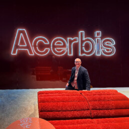 A man kneels (Ross Bonetti) alongside a bright red seating system with a glowing 